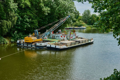 Boats sailing on river by trees