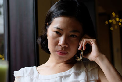 Portrait of young woman holding camera at home