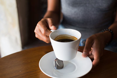 Midsection of woman holding coffee cup on table