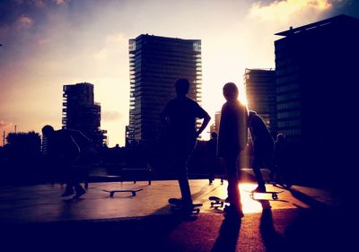 Silhouette people on city at sunset