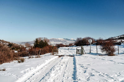 Snow covered field against clear blue sky