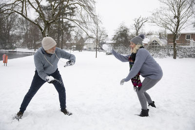 Senior couple enjoying snowball fight during winter