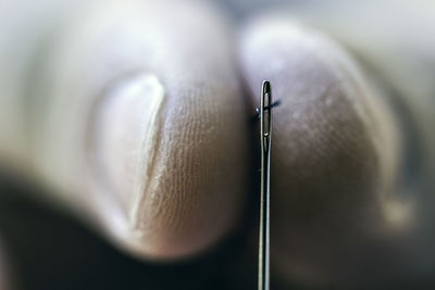 Extreme close-up of hand putting thread in needle