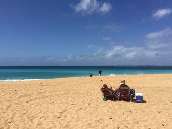 People on beach against blue sky