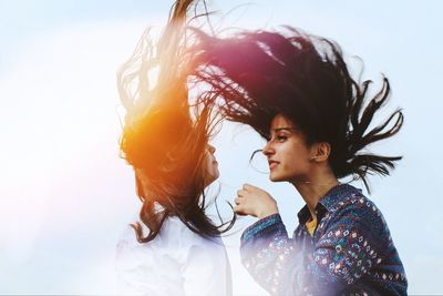 Female friends with tousled hair against sky