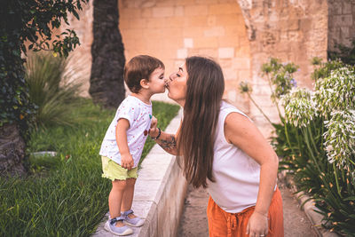 Mother and daughter kissing at park