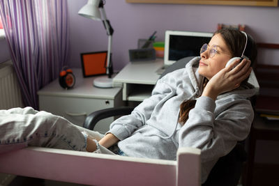 A young brunette girl gazes into the distance listening to music on wireless headphones.