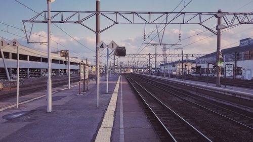 Railroad station platform against sky at sunset