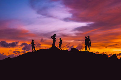 Silhouette people against dramatic sky during sunset