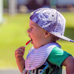 Cute boy eating lollipop while looking away outdoors