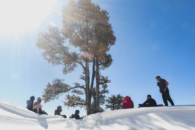 People on snow covered plants against sky