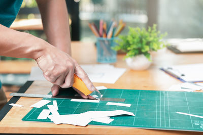 Midsection of person holding paper on table