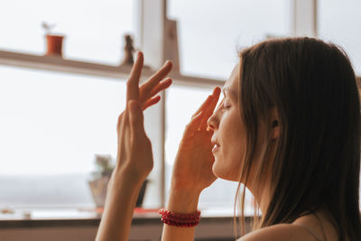 Side view of young woman looking through window