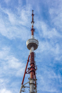 Low angle view of communications tower against cloudy sky