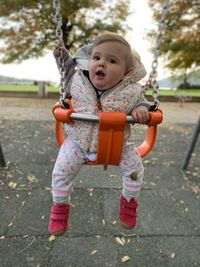Cute, little babygirl sitting on swing in playground - happy times with mom