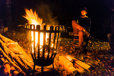 Young man sitting at campsite during night