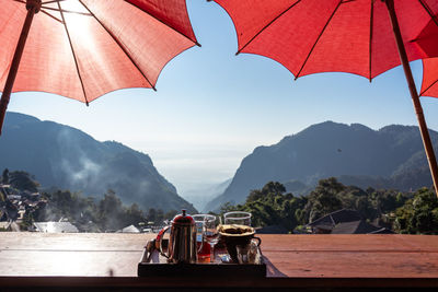 Umbrellas on table against mountain range