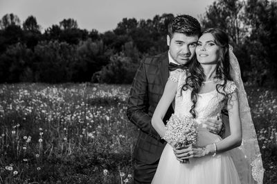 Happy young couple standing against plants