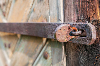 Close-up of an old, corroded and rusty padlock closing the wooden door. details of wood and metal