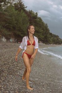 Smiling woman wearing bikini walking at beach