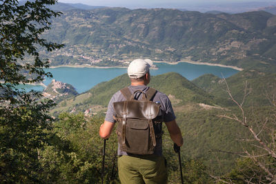 Rear view of man standing looking at view while standing on mountain