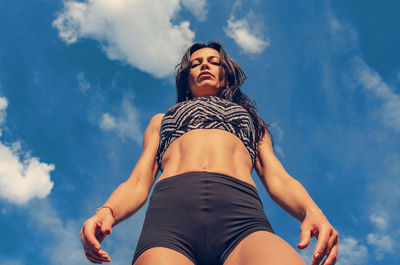 Fitness woman in shorts and top on a background of sky clouds