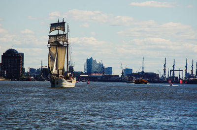 Sailboats in sea against sky in city