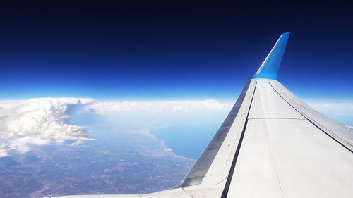 Airplane flying over landscape against blue sky