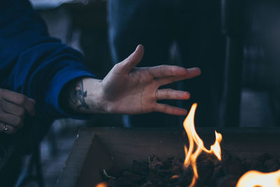 Close-up of human hand by fire