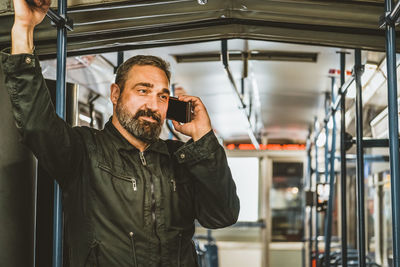 People, lifestyle, travel and public transport. attractive man talking on the phone in public bus .