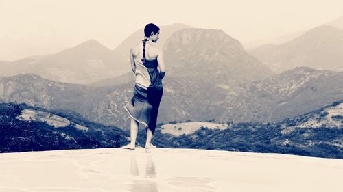 Full length rear view of woman in sarong standing against mountains
