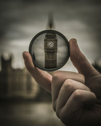 Close-up of hand holding lens against big ben