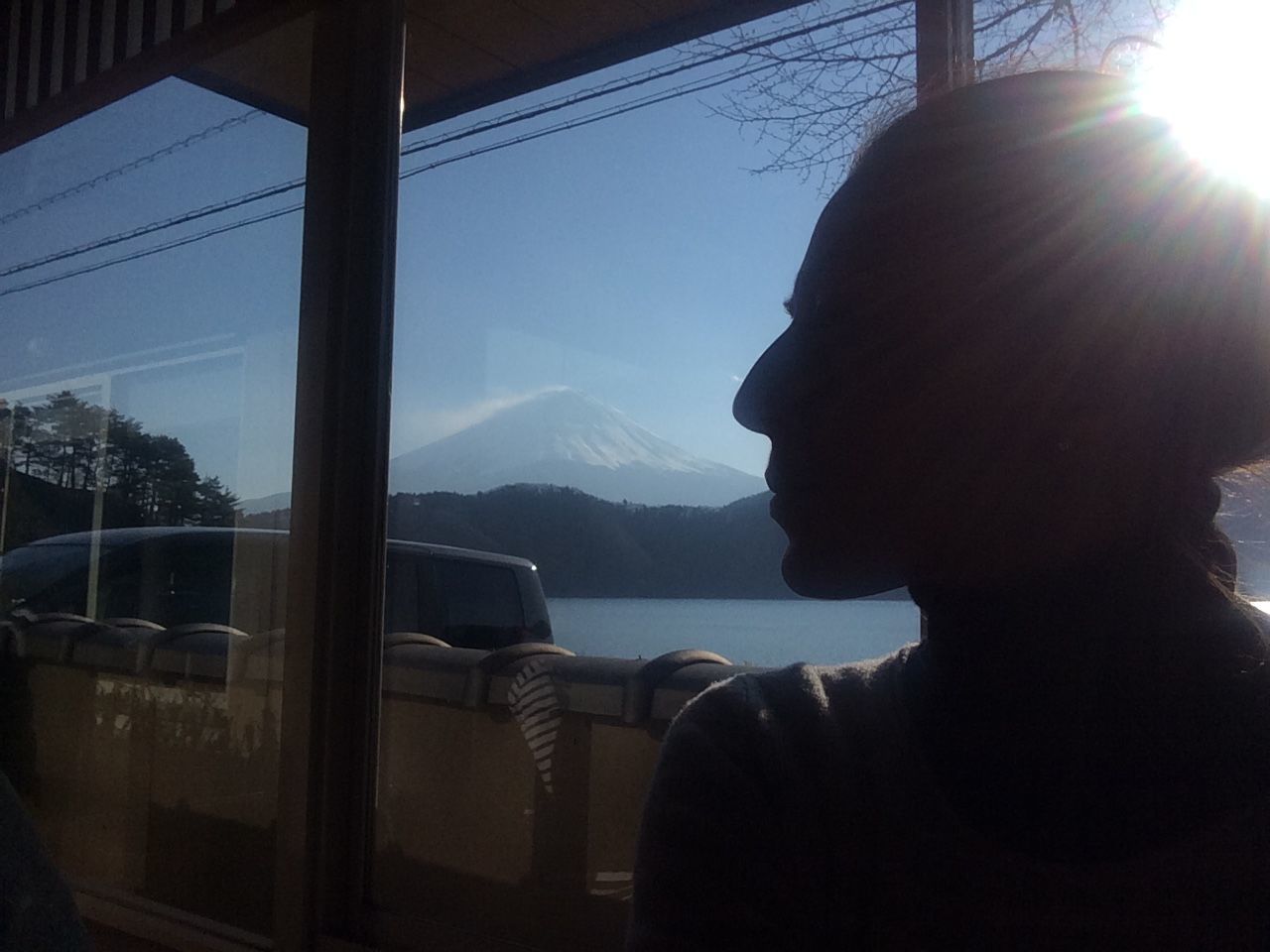 mountain, window, one person, sunlight, indoors, sky, sun, sunbeam, glass - material, mountain range, transparent, silhouette, water, vehicle interior, day, nature, transportation, mode of transport, sitting, looking through window