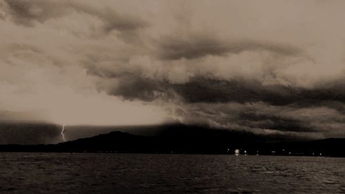 View of calm sea against storm clouds