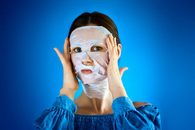 Portrait of woman wearing mask against blue background