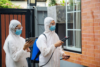 Man and wearing protective suit disinfecting house