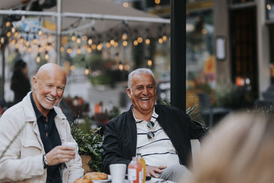 Happy senior man enjoying with friends at sidewalk cafe