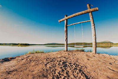 Wooden posts on beach against clear blue sky