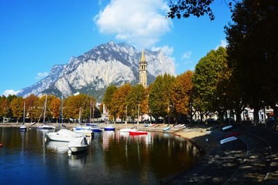 Boats in lake by trees against sky