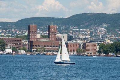 Sailboat on sea by buildings in city