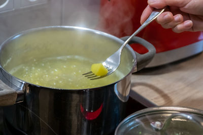 Woman cooking on cooker in the kitchen with hot steam and pots on a ceran stove to cook