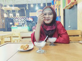 Portrait of smiling young woman sitting at restaurant