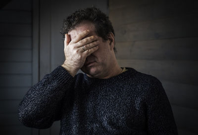 Close-up portrait of sad man against wall