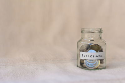 Close-up of coins with text over jar on white fabric