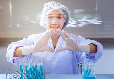 Portrait of female scientist holding laboratory equipment at desk