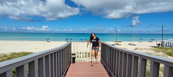 Rear view of woman walking on beach against sky