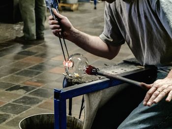 Midsection of male worker making glass in factory