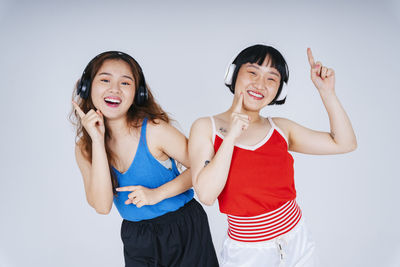 Lesbian couple listening music against gray background