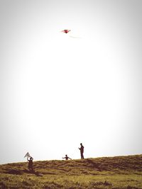 Silhouette man flying over field against clear sky