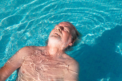 High angle view of man relaxing in swimming pool
